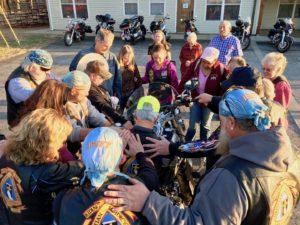 Christian bikers and cowboys alike pause to pray for a member of their chapter of the Christian Motorcyclists Association as they gather at church.